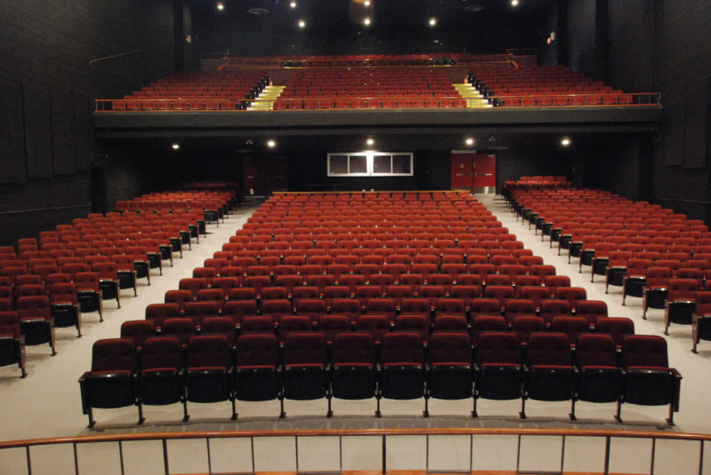 This image showcases a spacious and elegant theater venue featuring rows of plush red seats, offering clear sightlines to the stage. The setup suggests a perfect setting for live performances such as comedy shows, plays, or concerts. Its tiered seating design ensures an inclusive experience for audiences at all levels, making it ideal for hosting memorable events in a comfortable atmosphere. If this image represents a venue for an upcoming comedy show or performance, it sets the tone for a professional and engaging experience.