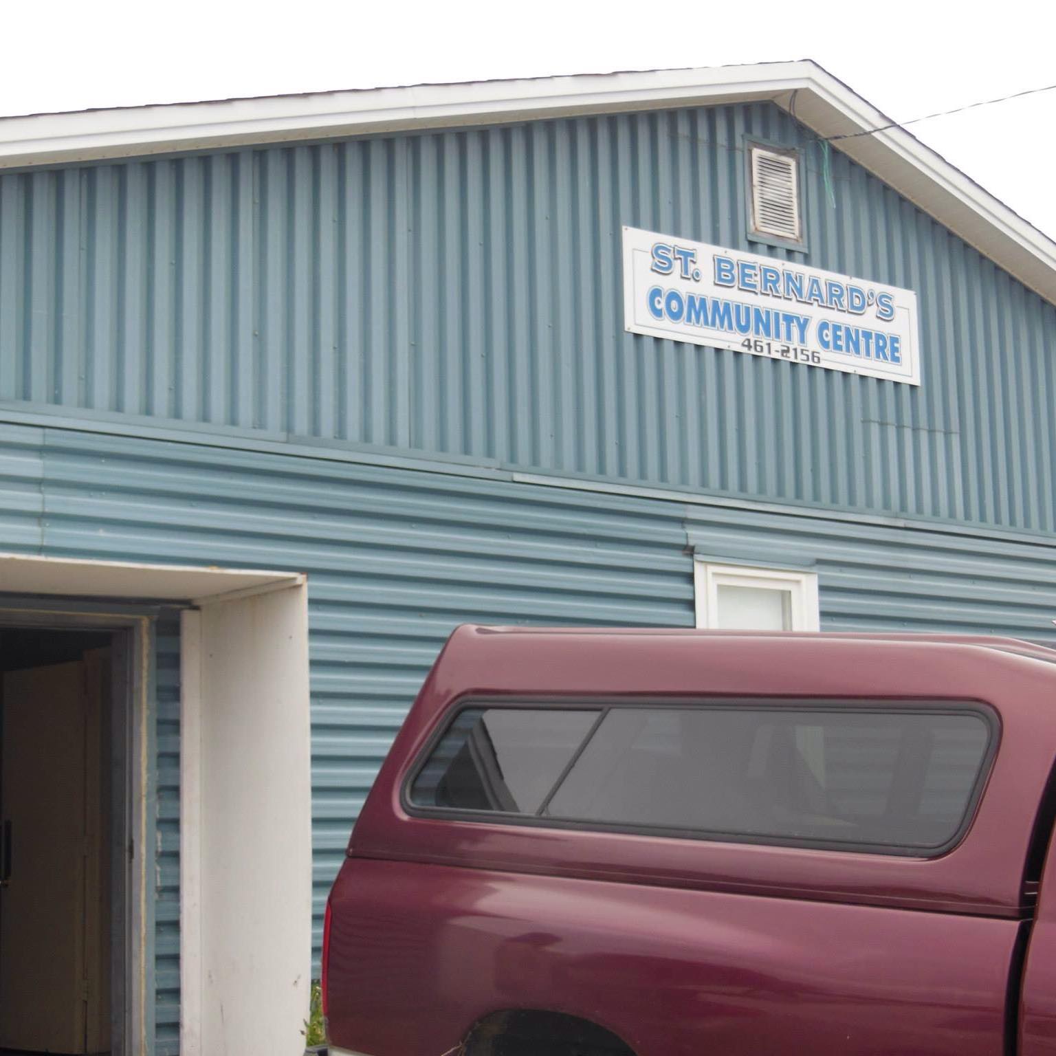 This photo shows the St. Bernard’s Community Centre, located in St. Bernard’s–Jacques Fontaine, Newfoundland and Labrador. Venue Features: The building has a distinct blue metal siding with a white-framed sign reading: ST. BERNARD’S COMMUNITY CENTRE 461-2156 The entrance is simple and accessible, and there's visible parking space directly out front (as seen with the parked truck). It serves as a local gathering hub for events, town functions, and community programming. This is a classic rural Newfoundland venue—perfect for a cozy, community-driven comedy night where the audience likely knows each other, and laughter fills the whole building.